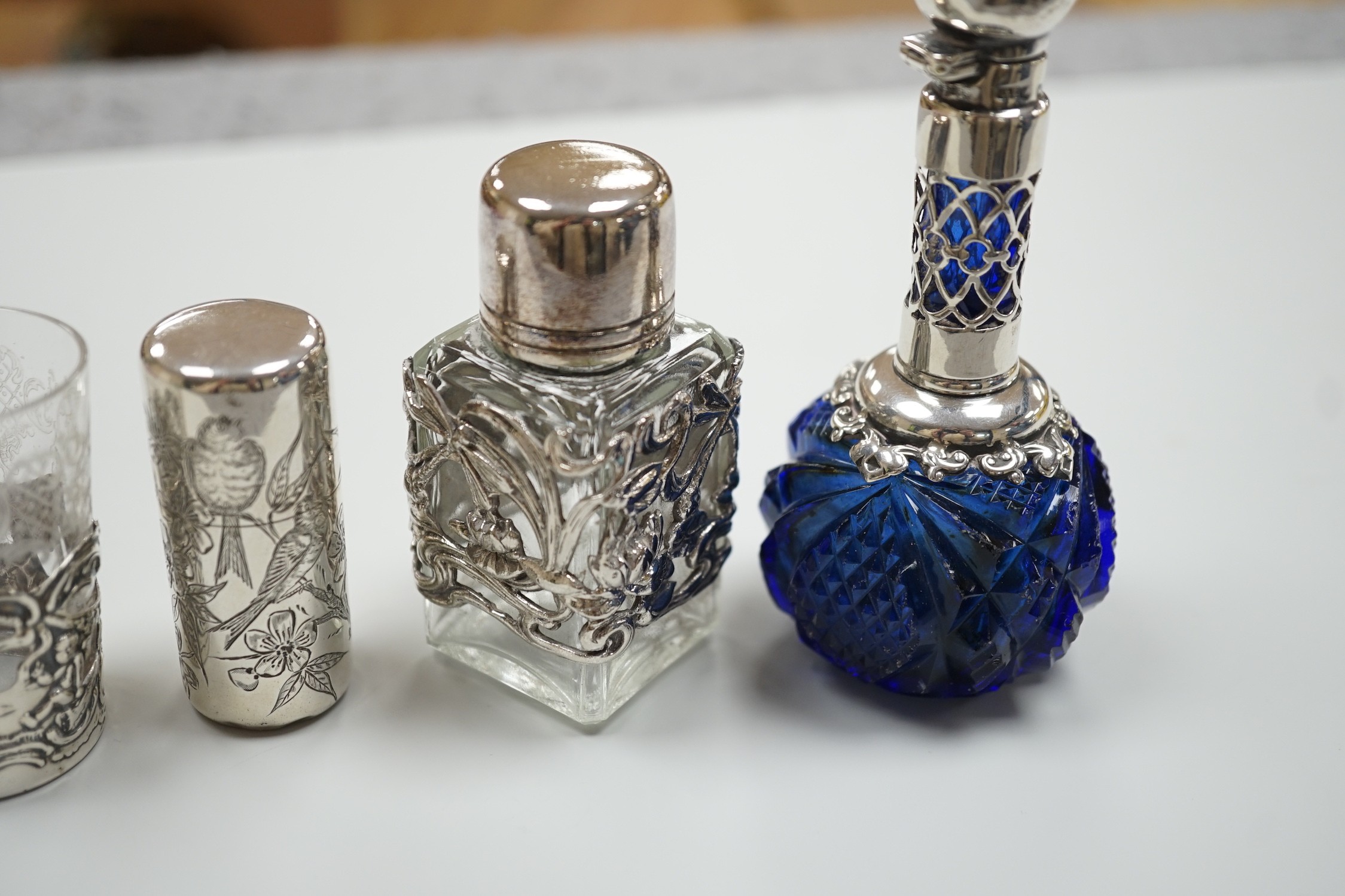 A late Victorian aesthetic engraved silver cylindrical scent bottle, by Sampson Mordan, London, 1881, 54mm, two other mounted glass scent bottles and a similar silver mounted demi tasse cup.